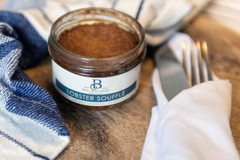 Open Ballancourt lobster soufflé jar with a blue napkin and table setting